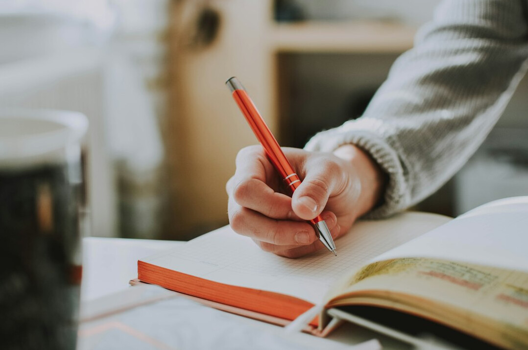 person writing notes in journal
